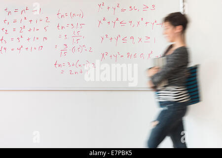 Young woman walking in front of whiteboard Stock Photo