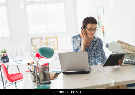 Senior business woman using cell phone and tablet pc in office Stock Photo