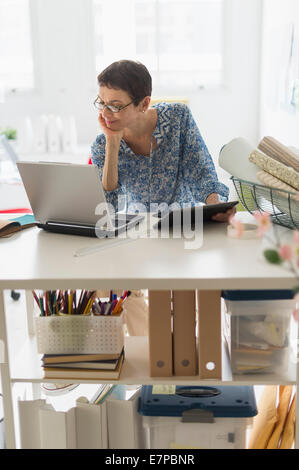 Senior business woman using cell phone and tablet pc in office Stock Photo