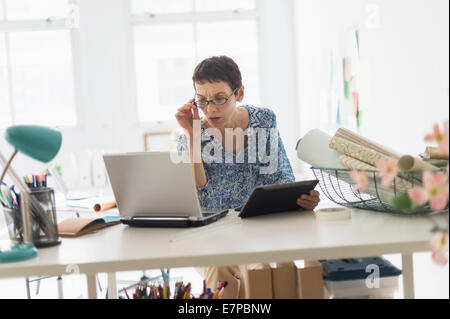 Senior business woman using laptop and tablet in office Stock Photo