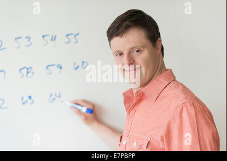 Man with down syndrome writing on whiteboard Stock Photo