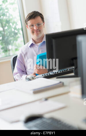 Man with down syndrome working in office Stock Photo
