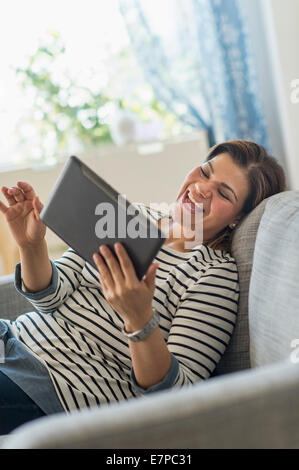 Portrait of happy woman lying on sofa with tablet pc Stock Photo
