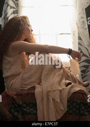 Portrait of stylish woman sitting in window sill Stock Photo