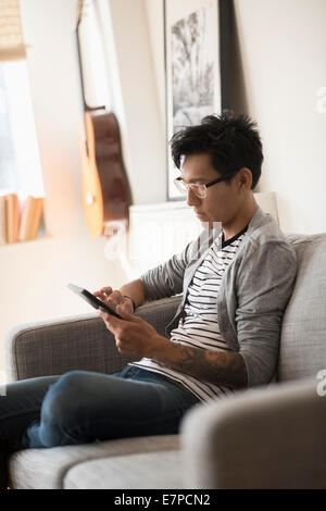 Man sitting on sofa and using tablet Stock Photo
