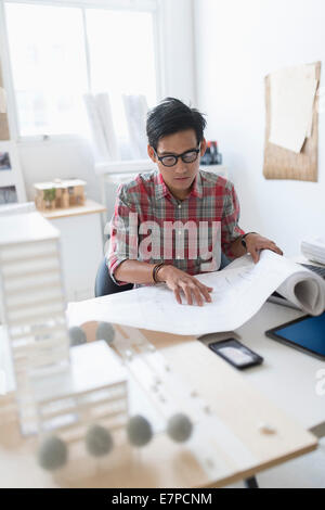 Architect looking at blueprints in office Stock Photo