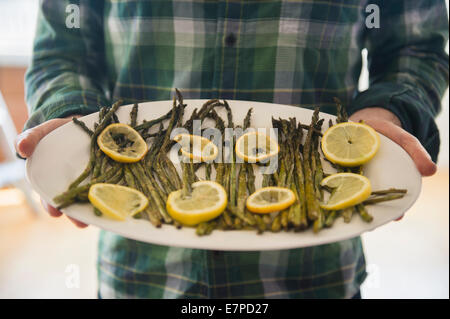 Man holding platter with asparagus and lemon Stock Photo