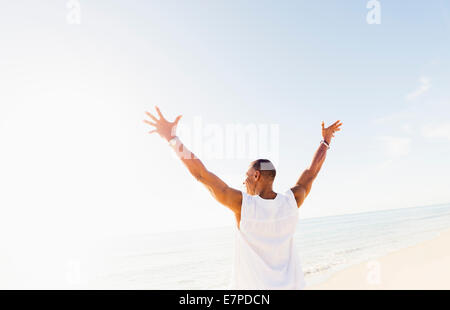 Man raising arms on beach Stock Photo