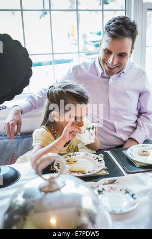 Father and daughter (4-5) eating together in dining room Stock Photo