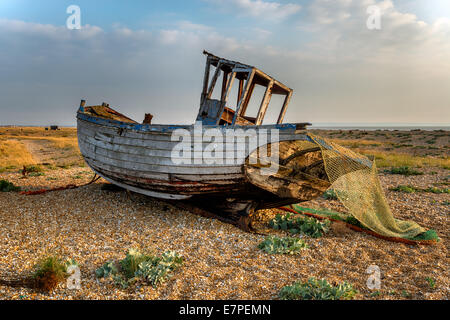 Old wooden fishing boat stranded on a shingle beach Stock Photo