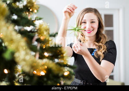 Young woman decorating Christmas tree Stock Photo