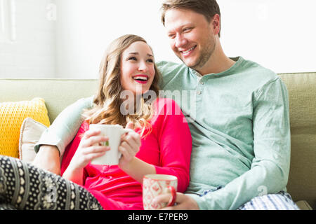 Young couple wearing pajamas sitting on sofa Stock Photo