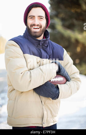 Portrait of man holding football outdoors Stock Photo