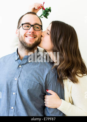 Woman kissing man under mistletoe Stock Photo