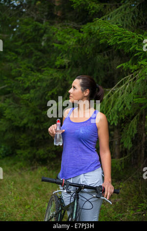 Pretty young woman drinks water outdoors summer Stock Photo