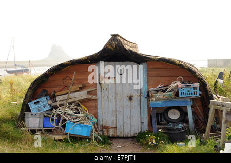 Old upturned Keel Boats now used for storage on the Island of Lindisfarne off of the Northumbrian coast in the north of England. Stock Photo