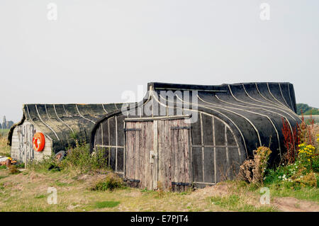 Old upturned Keel Boats now used for storage on the Island of Lindisfarne off of the Northumbrian coast in the north of England. Stock Photo