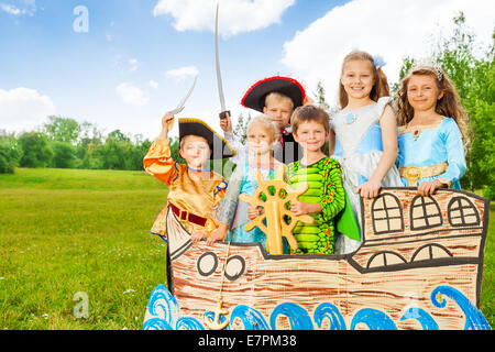 Happy kids in different costumes stand on ship Stock Photo