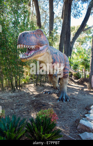 Life size Tyrannosaurus Rex dinosaur figures prowl the forest Stock Photo