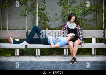 Romantic interracial young couple relaxing on park bench outside Stock Photo