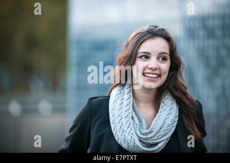 Candid portrait of happy young brunette woman smiling with copy space in urban setting Stock Photo