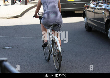 Rear view of a female riding a cycle in traffic, in Trafalgar Square, London Stock Photo