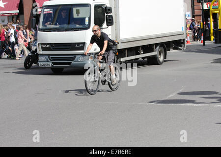 A cyclist and truck traveling along a road in London Stock Photo
