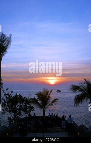 A small boat sails off into the sunset in Acapulco Stock Photo