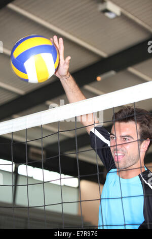 A volleyball player hitting the ball over the net. Stock Photo