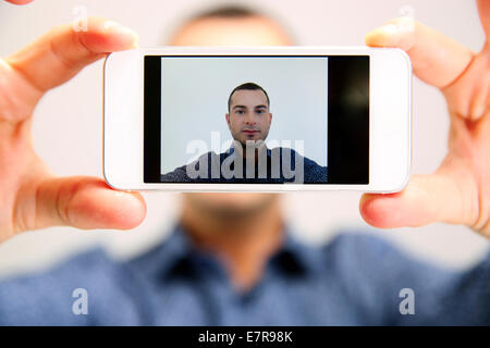 Handsome man taking selfie. Focus on smartphone Stock Photo