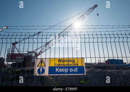 Warning construction site keep out sign with a crane in the background Stock Photo