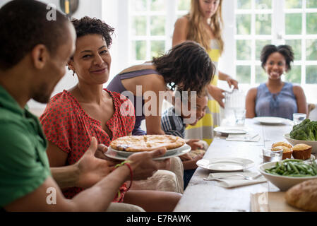 A family gathering, men, women and children around a dining table sharing a meal. Stock Photo