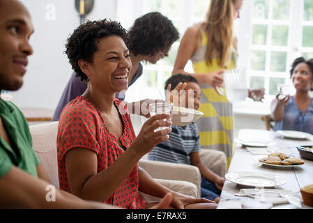 A family gathering, men, women and children around a dining table sharing a meal. Stock Photo