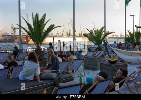 Young people relax with a drink at a beach bar on the Spree River at Landungsbrucke. Stock Photo