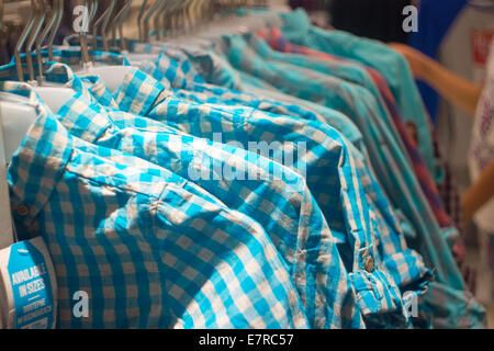 Various hipster shirts on hangers in store. Trendy clothes Stock Photo