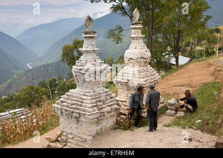 Eastern Bhutan, Trashi Yangtse, workers carrying construction stone resting by old stone chortens Stock Photo