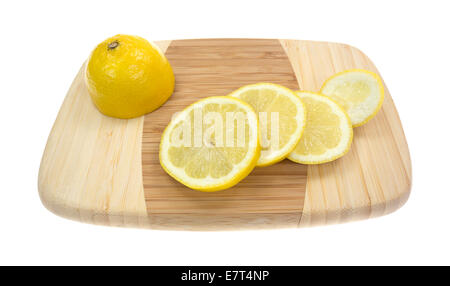 Half a lemon with several slices on a small bamboo cutting board. Stock Photo