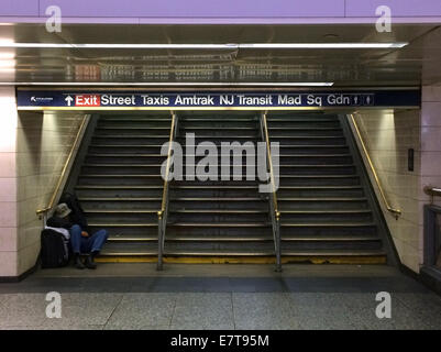 2 AM at Penn Station - a homeless man sleeps on the steps of an exit from Pennsylvania Station in downtown Manhattan (New York City). Stock Photo