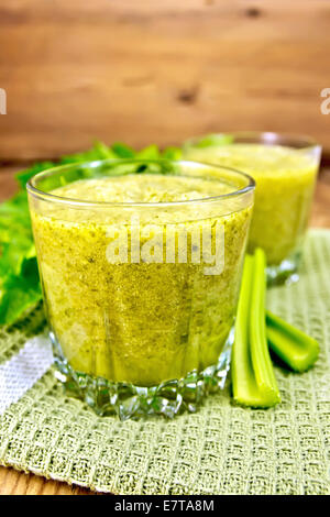 Two glassful with a cocktail of celery on a napkin, stems and leaves of celery on a wooden boards background Stock Photo