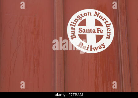 Close-up shot of a Burlington Northern Santa Fe (BNSF) branding logo on the side of a red covered hopper rail car in a rail yard Stock Photo