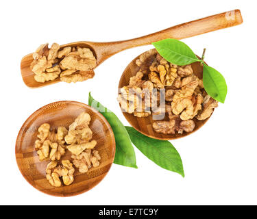 Handful of walnuts in wooden bowls, scoop and green leaves isolated on white background. Closeup. Stock Photo