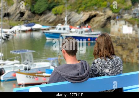 A young couple sitting on a bench in Newquay Harbour Cornwall England uk Stock Photo