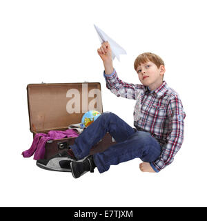 Boy sitting near open suitcase with paper airplane in hand isolated on white background Stock Photo