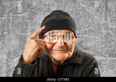 Elderly woman has an idea, pointing with finger on her head. Stock Photo