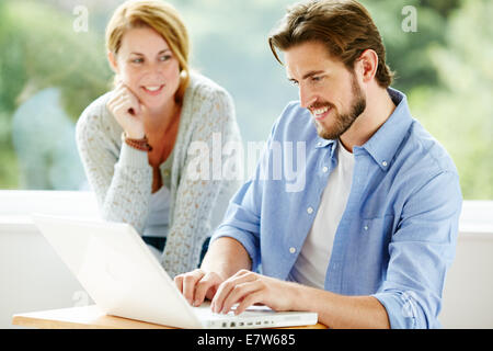 Happy couple looking at laptop Stock Photo