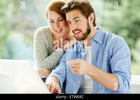 Happy couple looking at laptop Stock Photo