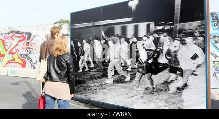 Berlin, Germany. 24th Sep, 2014. Visitors look at historic pictures on display on large panels at the former border crossing on Bornholmer Strasse (today known as the square 'Platz des 9th November') in Berlin, Germany, 24 September 2014. Berlin is commemorating the 25th anniversary of the Fall of the Berlin Wall on 9 November 2014. Photo: STEPHANIE PILICK/dpa/Alamy Live News Stock Photo