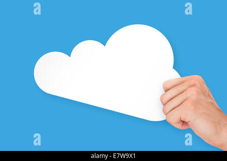 Hand holding white, empty, blank cloud technology cardboard, isolated on blue background. Stock Photo