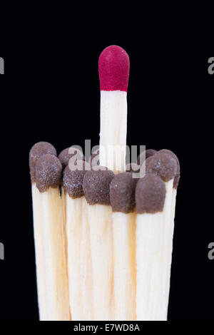Leadership concept, red headed match standing out from the crowd on dark background. Stock Photo