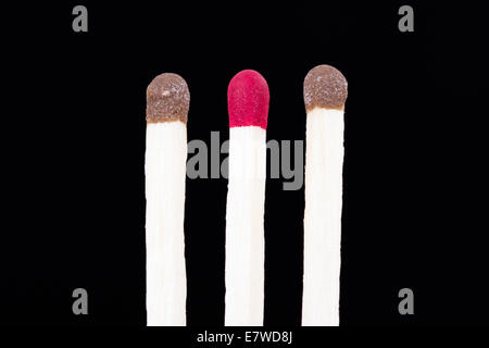 Leadership concept, red headed match standing out from the crowd on dark background. Stock Photo